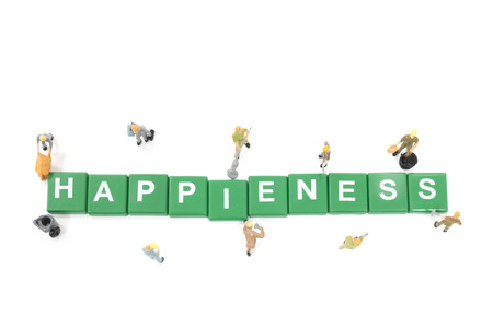 Miniature worker team building word Happiness on white backgroundの写真素材
