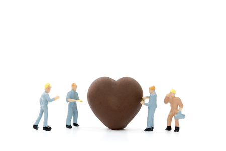 Miniature worker making heart shaped chocolate on white background , valentine concept.の写真素材