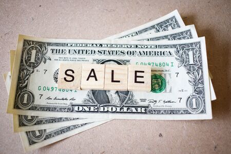 Wooden block word sale and Dollar banknote on wooden backgroundの写真素材