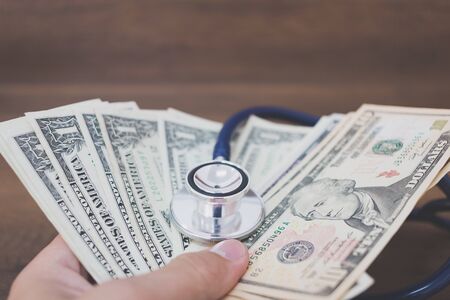 Stethoscope on dollar banknote money on wooden background , Concept of health care costsの写真素材