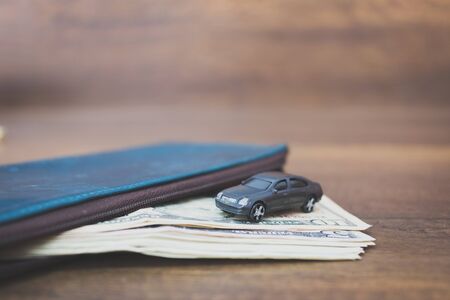 Car model on dollar banknotes , cost of buying a car on wooden backgroundの写真素材