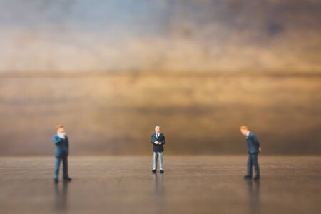 Miniature people businessman standing on wooden backgroundの写真素材
