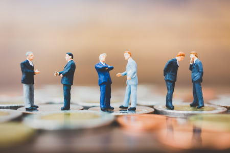 Miniature people businessman standing on money with  wooden backgroundの写真素材