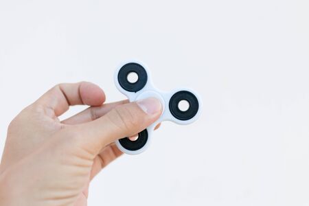 Hands holding popular fidget spinner toy on white backgroundの写真素材