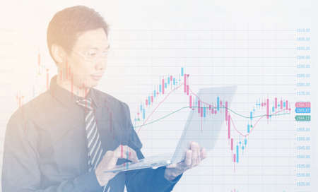 Asian businessman using laptop with business charts and graphsの写真素材