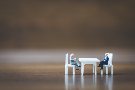 Miniature people team sitting down on the chair and space for textの写真素材