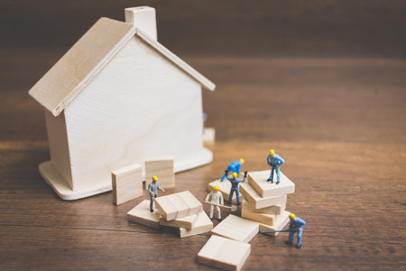 Miniature workers team build a wooden houseの写真素材