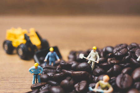 Miniature people working on roasted coffee beansの写真素材