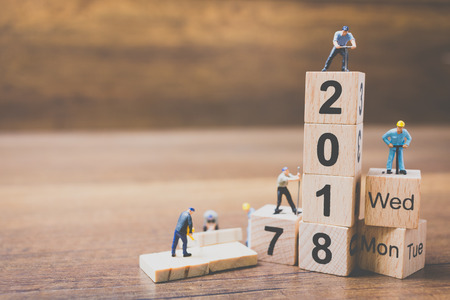 Miniature worker team building wooden block number 2018 on wooden backgroundの写真素材