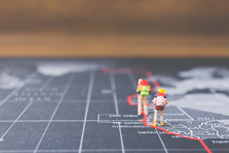 Miniature people backpacker walking on world map, Tourism and travel concept