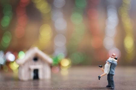 Miniature couple hugging on wooden floor with colorful bokeh background , Success family conceptual.の写真素材