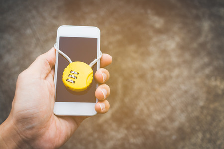Hand holding locked smartphone with padlock , Security and protection conceptの写真素材