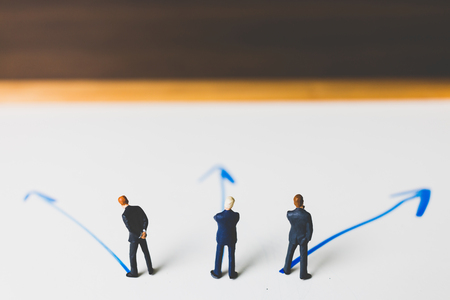 Miniature Businessman standing on arrow pathway , Business decision concept.の写真素材