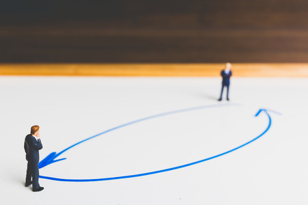 Miniature Businessman standing on arrow pathway , Business decision concept.の写真素材
