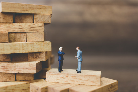 Miniature people: Businessman standing on wood block