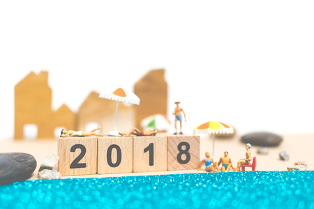 Miniature people wearing swimsuit relaxing on the beach With Wooden block number 2018の写真素材