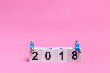 Miniature people : Couple sitting on wooden block number 2018 , Valentine's day concept