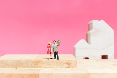 Miniature people : Couple with house on pink background , Valentine's day conceptの写真素材