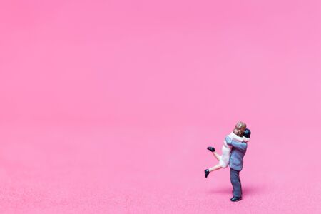 Miniature couple hugging on pink background, valentine conceptの写真素材