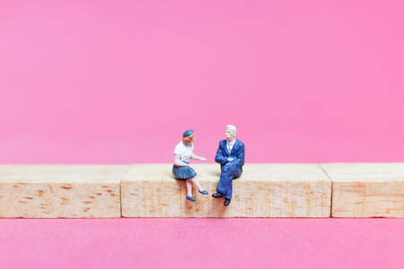 Miniature people : Couple sitting on wooden block , Valentine's day conceptの写真素材