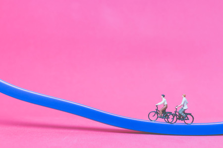 Miniature people travellers with bicycle on The bridge on pink background , Valentine's day conceptの写真素材