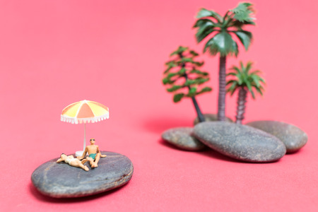 Miniature people wearing swimsuit relaxing on the rock with pink background , Valentine's day conceptの写真素材