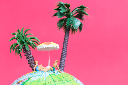 Miniature people wearing swimsuit relaxing on The globe with pink background , Valentine's day conceptの写真素材