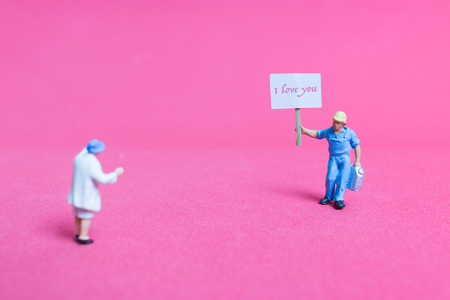 Miniature people: Holding paper board "I love you " on pink background , Valentine's day conceptの写真素材