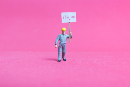 Miniature people: Holding paper board "I love you " on pink background , Valentine's day conceptの写真素材