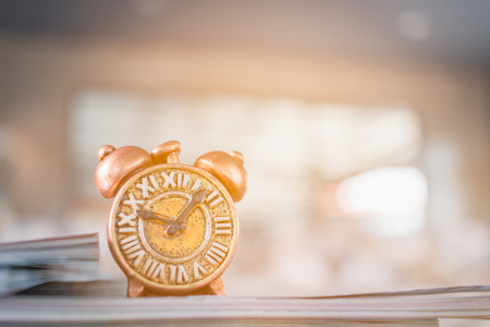 Ancient clock and stack of book with warm lighting backgroundの写真素材