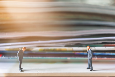 Miniature people: Businessman standing and stack of book with warm lighting backgroundの写真素材