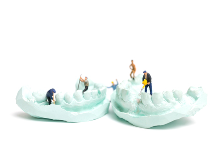 Miniature Worker team is filing fake teeth and placing them in a denture made with plaster. Dental...