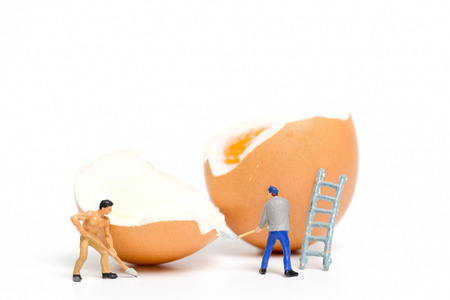 Miniature people work at Easter-eggs for Easter day on white backgroundの写真素材