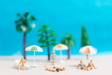Miniature people wearing swimsuit relaxing on the beach with blue backgroundの写真素材