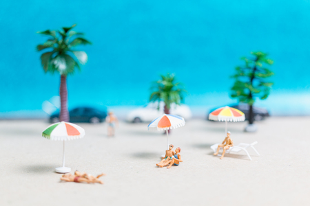 Miniature people wearing swimsuit relaxing on the beach with blue backgroundの写真素材