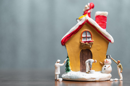 Miniature people painting house and Santa Claus sitting on the roof , Merry Christmas and happy holidays concept.の写真素材