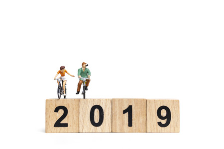 Miniature people : Friend Group ride bicycle with wooden number  2019 , Happy New Year  concept.