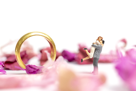 Miniature people : Couple hug in The pink garden with a wedding ring isolate on white backgroundの写真素材
