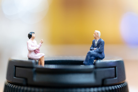 Miniature people : businessman and woman sitting on chair and copy space for text