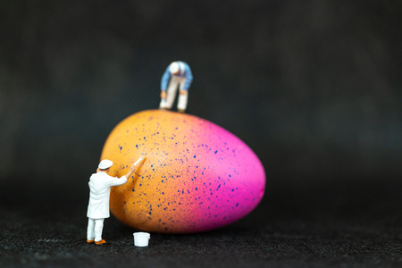 Miniature people  painting Easter-eggs for Easter day on black backgroundの写真素材