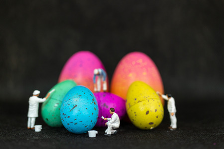 Miniature people  painting Easter-eggs for Easter day on black backgroundの写真素材