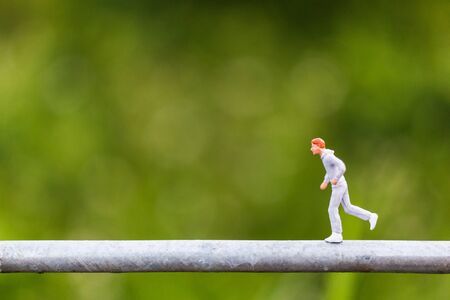 Miniature people : Young people running on a wire with green background
, Healthy lifestyle and sport concepts.の写真素材