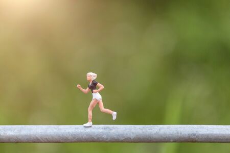 Miniature people : Young people running on a wire with green background, Healthy lifestyle and...