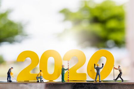 Miniature people : Worker team build wooden number 2020 with blurred tree backgroundの写真素材