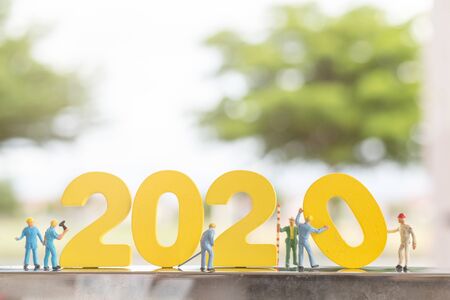 Miniature people : Worker team build wooden number 2020 with blurred tree backgroundの写真素材