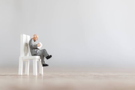 Miniature people: Businessman reading book on  chair , Education or business concept.の写真素材