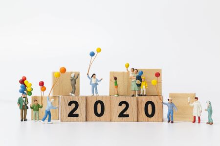 Miniature people : Happy family holding balloon on wooden block number 2020  , Happy new year...