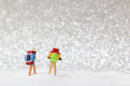 Miniature people: backpacker walking on snow background . Winter concept.の写真素材