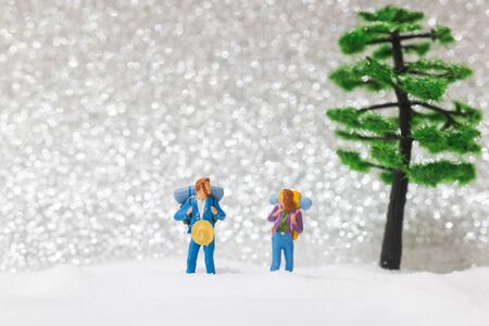 Miniature people: backpacker walking on snow background . Winter concept.の写真素材
