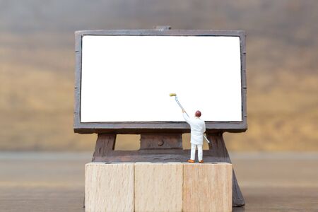 Miniature people: Painter holding a brush on The stair at The front of a whiteboard and space for textの写真素材